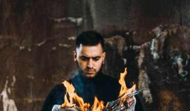 man holding burning newspaper